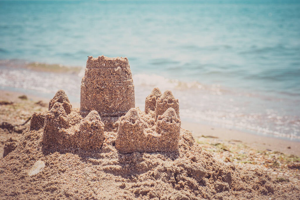 Castillo de arena de pie en la playa. Concepto de vacaciones de viaje. - Foto, Imagen