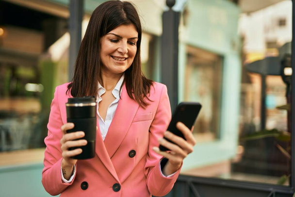 Geschäftsfrau mittleren Alters benutzt Smartphone im Freien und tippt eine Nachricht - Foto, Bild