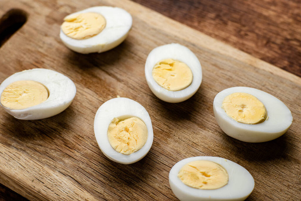 Halves of boiled chicken eggs on a wooden background. - 写真・画像