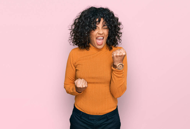 Young hispanic woman wearing casual clothes celebrating surprised and amazed for success with arms raised and eyes closed. winner concept.  - Photo, Image