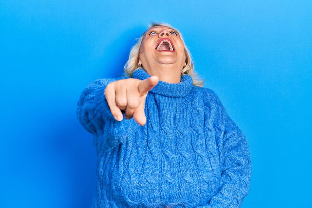 Blonde Frau mittleren Alters in lässiger Kleidung lacht dich an, zeigt mit der Hand über den Körper in die Kamera, schämt sich  - Foto, Bild