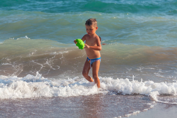 Antalya, Türkei-26. August 2013: Netter kleiner Junge, der an einem heißen Sommertag in Antalya, Türkei, am Strand mit Plastikspielzeug spielt.  - Foto, Bild