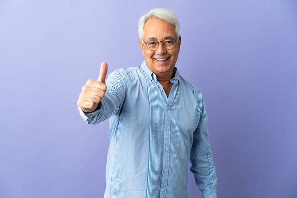 Middle age Brazilian man isolated on purple background with thumbs up because something good has happened - Foto, immagini