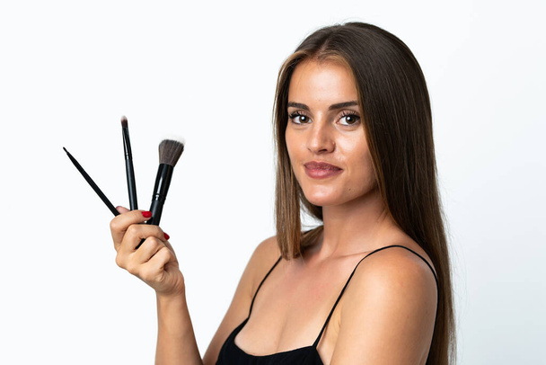 Junge uruguayische Frau isoliert auf weißem Hintergrund hält Make-up-Pinsel - Foto, Bild