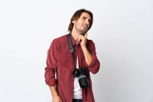 Jonge fotograaf man geïsoleerd op witte achtergrond denken een idee tijdens het kijken omhoog - Foto, afbeelding