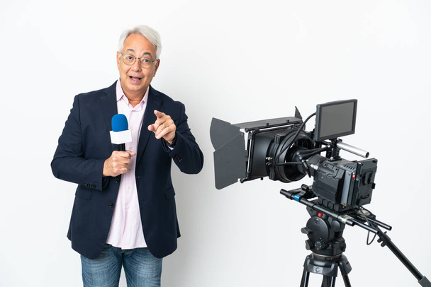 Reporter Middle age Brazilian man holding a microphone and reporting news isolated on white background surprised and pointing front - Foto, Imagen
