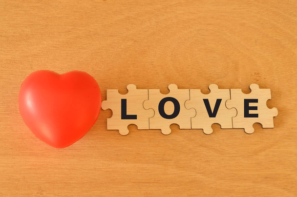 Forma de corazón rojo y rompecabezas de madera con texto LOVE - Foto, imagen