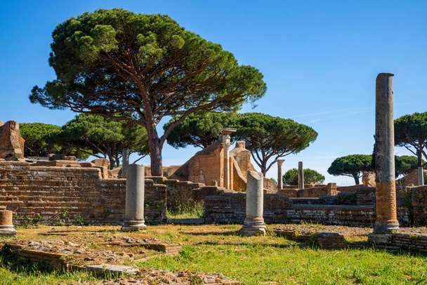 Rome Ostia Antica site, ruins of marble columns with brick buildings from the imperial era a in the archaeological park of Ostia Antica in summer with blue sky. Rome Italy, Europe. - Photo, Image