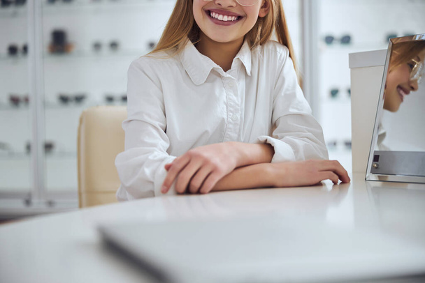 Good looking school girl spending time at the desk in optician center - Photo, Image