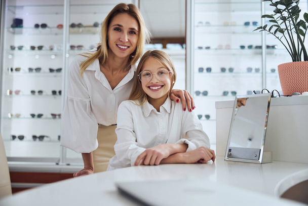 Happy friendly family wearing casual clothes posing at the photo camera in optician shop - Photo, Image
