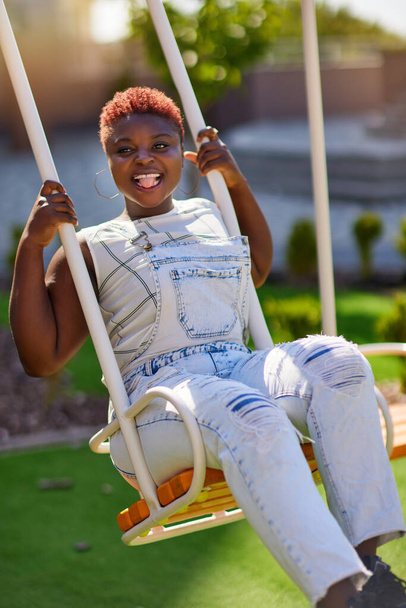 excited young woman having fun on swing, enjoying childish lifestyle - Foto, Imagen