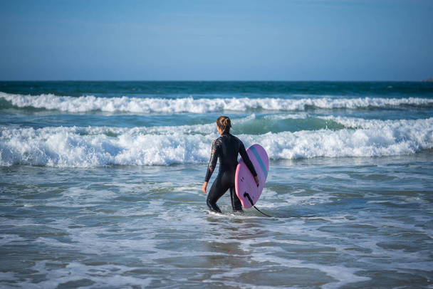 Ragazza con una tavola da surf supera le onde. Concetto: Superare, Determinazione, incredibile bellezza - Foto, immagini