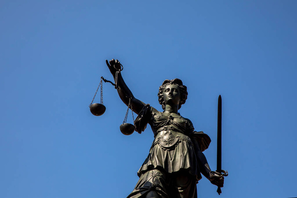 Gerechtigkeitsdame am Römer in Frankfurt am Main symbolisiert Gerechtigkeit mit Schwert und Waage unter blauem Himmel. - Foto, Bild