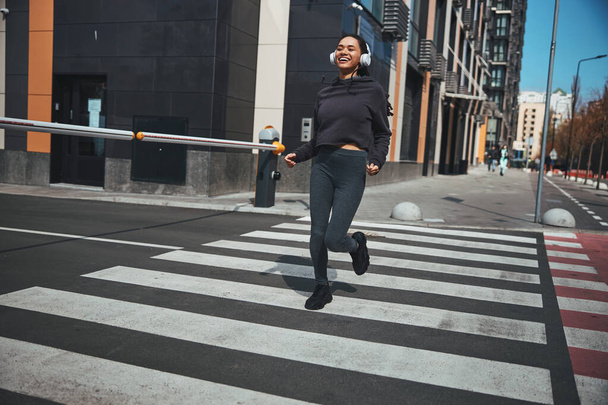 Cheerful sporty lady jogging in the city center - Zdjęcie, obraz