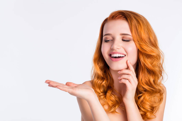 Photo portrait of pretty girl with curly red hair smiling looking blank space keeping on hand isolated on white color background - 写真・画像