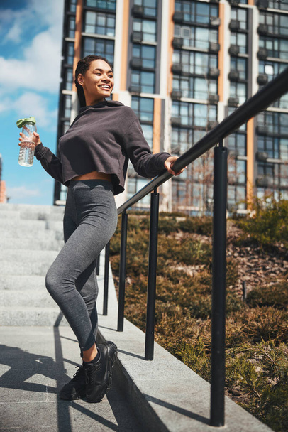 High-spirited attractive slim female standing on the concrete staircase - Foto, Bild