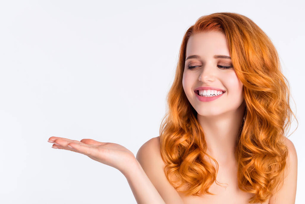 Photo portrait of pretty girl with curly red hair smiling looking keeping blank space on hand isolated on white color background - Photo, image