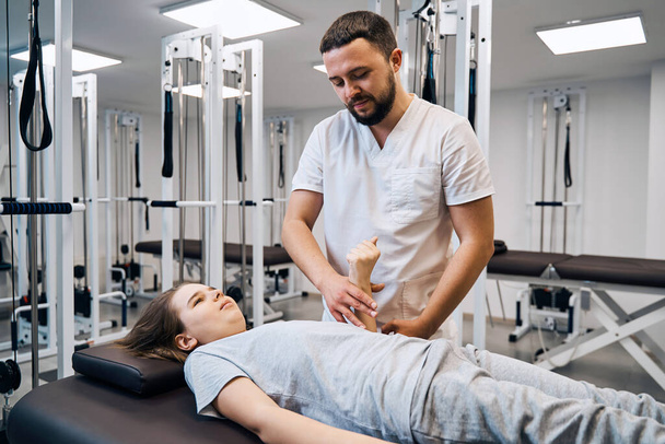 Portrait of physiotherapist massages girls hand in physio room. Professional pediatric therapist - Valokuva, kuva