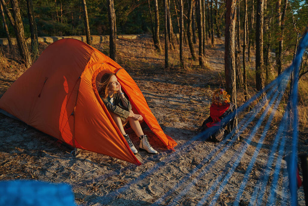 Kadın gün batımını izlerken çadırda dinleniyor. - Fotoğraf, Görsel