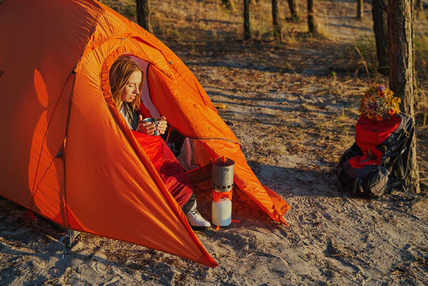 Nainen piilossa teltassa, kun ruoanlaitto teetä kaasupoltin - Valokuva, kuva