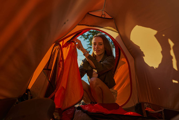 Female is sitting outside of tent entrance - 写真・画像