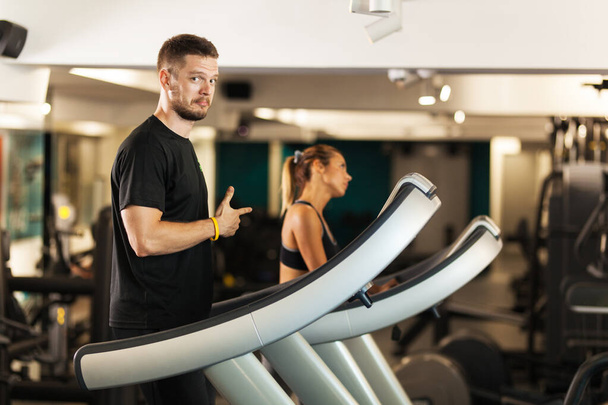 Couple working out on a treadmil in a fitness club - Фото, изображение