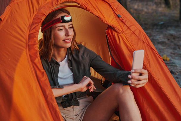 Kobieta turystka z palnikiem głowy robi selfie w namiocie - Zdjęcie, obraz