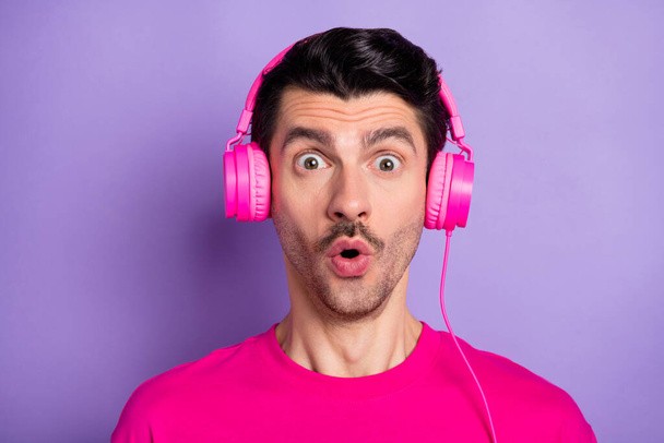 Fotografie mladého šokovaný překvapený muž ve sluchátkách vidět velký prodej sleva izolované na fialovém pozadí - Fotografie, Obrázek