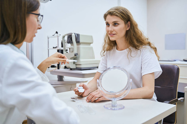 Güzel genç bir kadın klinikte göz doktoruyla görüşüyor. - Fotoğraf, Görsel