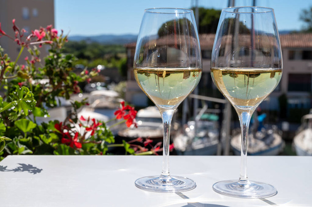 Verano en la Riviera Francesa Costa Azul, bebiendo vino blanco frío y seco de Cotes de Provence en la soleada terraza al aire libre en Port Grimaud, Var, Francia con barcos y yates en el fondo - Foto, imagen