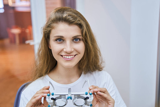 陽気若い女性が光学試験レンズフレームを保持 - 写真・画像