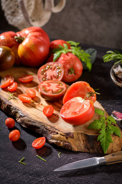 Large variety of tomatoes on rustic kitchen counter. Preparation of tomato sauce. - Fotó, kép