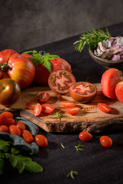 Large variety of tomatoes on rustic kitchen counter. Preparation of tomato sauce. - Fotó, kép