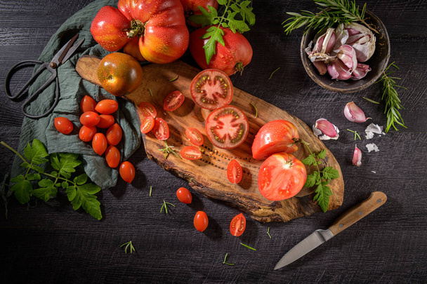 Large variety of tomatoes on rustic kitchen counter. Preparation of tomato sauce. - Φωτογραφία, εικόνα