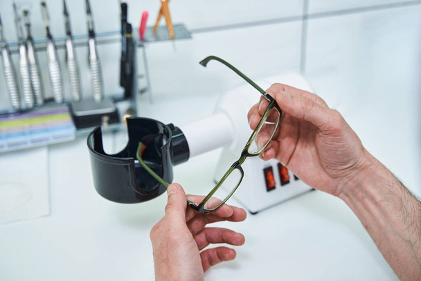 Male optician hands holding glasses with green frame - Foto, Imagen