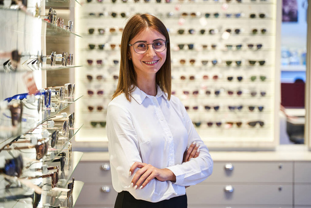 Vidám fiatal nő szemüvegben áll az optikai boltban - Fotó, kép