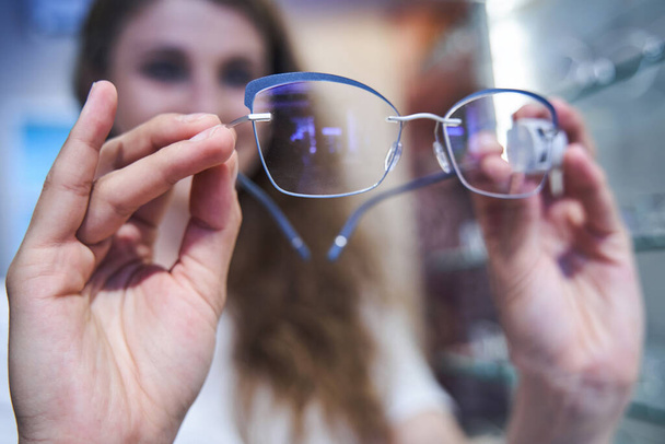 Junge Frau wählt Brille im Optikgeschäft - Foto, Bild