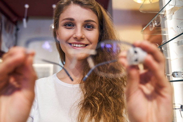Veselá žena s brýlemi stojící v optickém obchodě - Fotografie, Obrázek