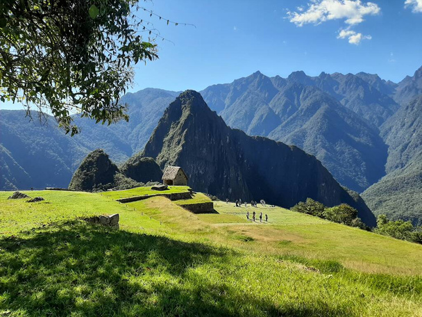 Se observla montaa Huayna Picchu, con un cielo totalmente despejado, con muito áreas verdes, se puede ver algunas ruinas y algunos turistas. - Foto, Imagem