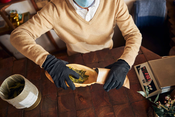 Trabalhador masculino colocando folhas de chá em bolsa de papel kraft - Foto, Imagem