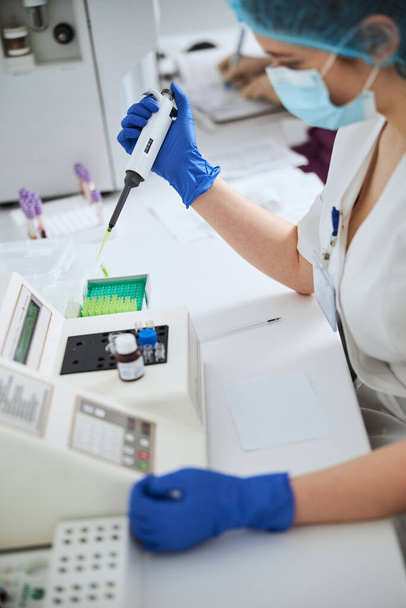 Biochemist using a pipettor for conducting a hematological test - Photo, Image