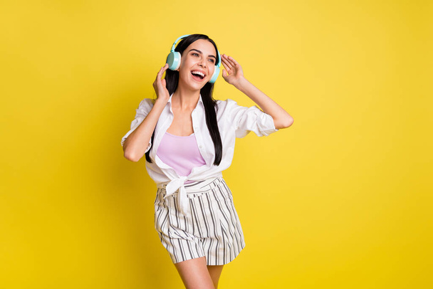 Photo of stunning happy young woman hold wear headphones look empty space dream isolated on yellow color background - Fotografie, Obrázek