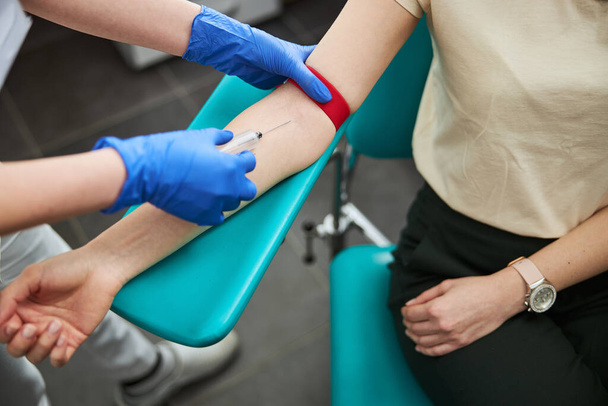 Professionelle Phlebotomin bei der Durchführung einer Venenpunktion - Foto, Bild