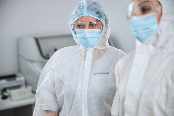 Woman in a protective face mask and her coworker - Photo, Image