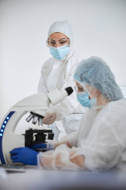 Scientists in hazmat suits examining a viral specimen - Фото, изображение