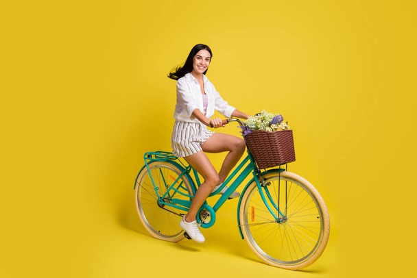 Full length photo of happy charming lady ride bicycle summer mood isolated on yellow color background - Fotó, kép