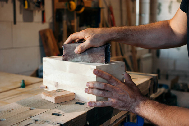Carpenter sanding wooden box - Фото, изображение