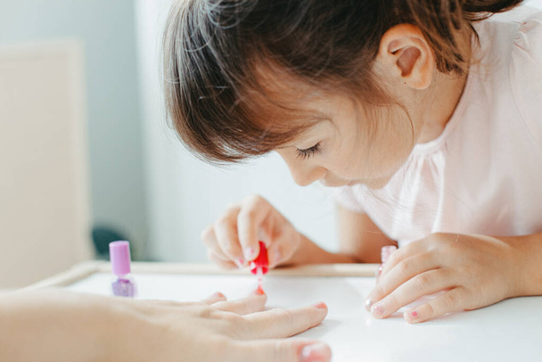 preschooler girl with interest paint nails her moms - 写真・画像