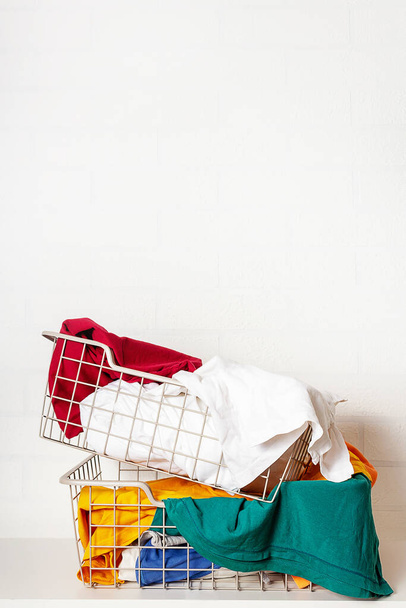 Huge stack of colorful clothes in baskets in laundry room. Improper storage of things, mess, disorder. Getting rid of unnecessary things and clothes. Copy space on top.  - Fotó, kép