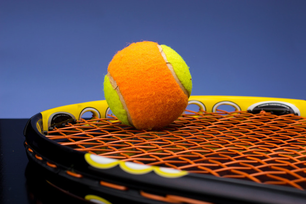 Pelota de tenis para niños con raqueta de tenis sobre fondo azul
 - Foto, Imagen